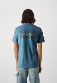 Camiseta de algodón azul con un gráfico colorido que lleva la palabra "O'Neill" en la parte de atrás, de manga corta y con un corte relajado.