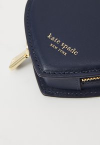 Marineblaue Leder-Sechseck-Tasche mit goldenen Hardware-Elementen und eingeprägtem "kate spade NEW YORK"-Logo. Verfügt über einen Reißverschluss und saubere Nähte.