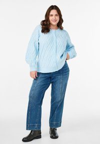 Ljusblå stickad cardigan med flätstickat mönster, med rund halsringning och knappstängning. Matchad med vida denimjeans och svarta ankelstövlar.