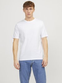 T-shirt en coton blanc à manches courtes, col rond et coupe décontractée, associé à un jean en denim bleu. Design simple et minimal.