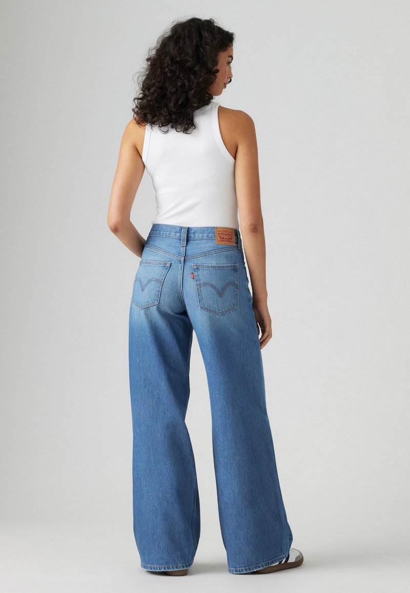 Jeans a gamba larga in denim chiaro, caratterizzati da un'alta vita, iconici taschini posteriori e un'etichetta in cuoio marrone sul passante posteriore.