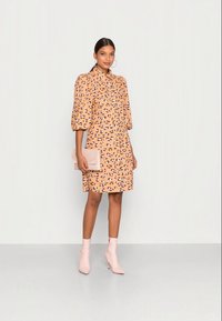 Vestido de manga curta, pêssego, com padrão de estampa de leopardo, combinado com uma mala de mão rosa clara e botas de tornozelo a condizer. Tecido suave, comprimento acima do joelho.