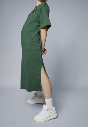 Grøn midi-kjole i blød bomuld med korte ærmer og sideslidser, stylet med hvide sneakers og ankellange sokker.