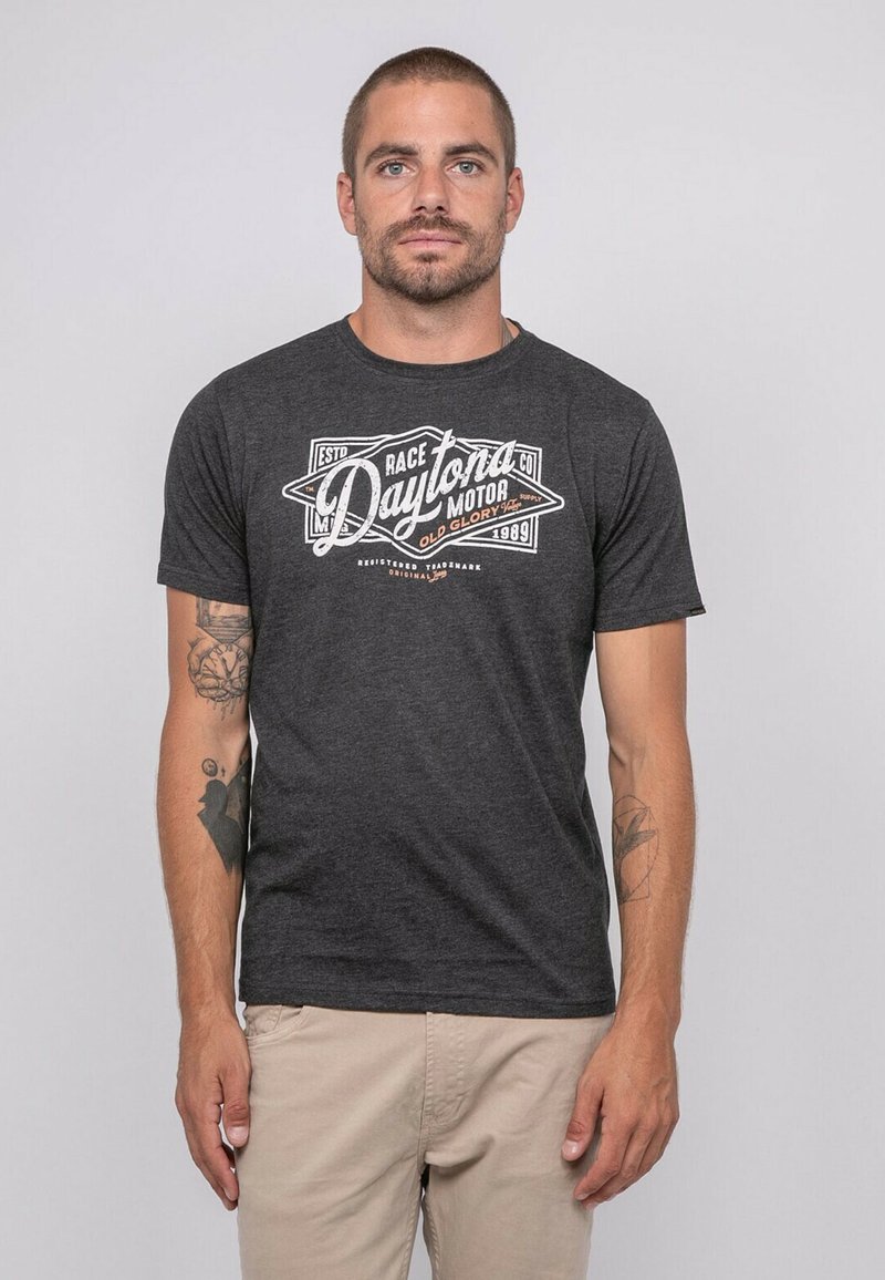 T-shirt en coton gris foncé avec un imprimé graphique blanc portant "Daytona Motor" et des éléments décoratifs à l'avant. Manches courtes, encolure ronde.