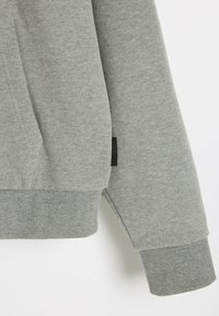 Szara bluza z ribbowanymi mankietami i dołem. Wykonana z miękkiego materiału, posiada boczną metkę oraz luźny krój. Gładka tekstura z minimalnymi detalami.