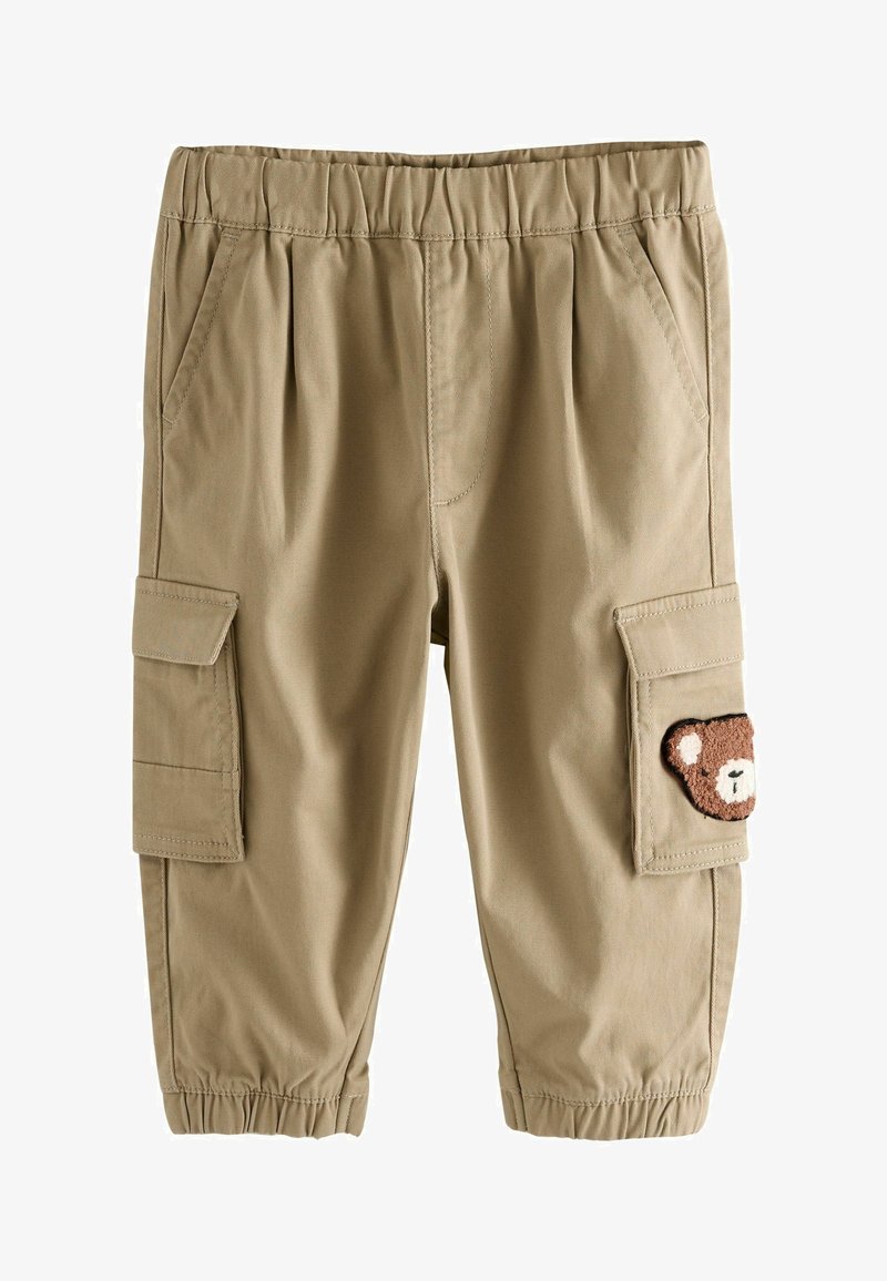 Tan színű, gumis derekú cargo nadrág, oldalsó zsebekkel, a jobb cargo zsebén medve folttal. Simára szőtt anyag.