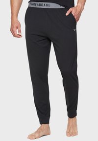 Sorte loungebukser lavet af blødt stof, med en grå elastisk talje med "THREADBARE" logo, tapered ben og sidelommer.