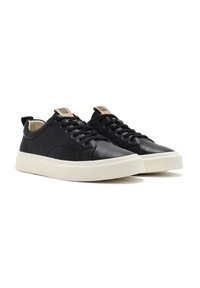 Sneakers in pelle nera con una finitura liscia, dotati di suole in gomma bianca, lacci rotondi e un accento marrone sulla linguetta.