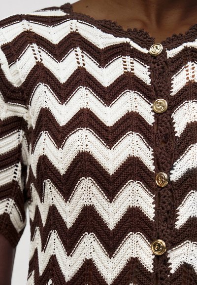 Cardigan en maille brun et blanc à motif chevrons avec boutons dorés et bords festonnés.