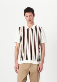 Bela kratka srajca s kratkimi rokavi, okrašena z navpičnimi črtami v rjavi, bež in temno rdeči barvi. Gladka tekstura s klasičnim ovratnikom.