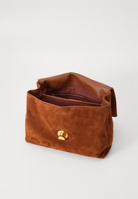 Brown suede bag with a textured finish, featuring a gold accent button and a zippered interior pocket. Open top design for easy access.