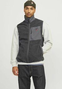 Fleece vest in donkergrijs met een half-rits ontwerp, voorzien van een grijze borstzak, hoge kraag en contrasterende grijze mouwen.