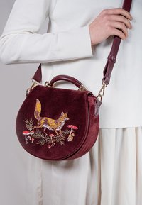 Runde handbag aus burgunderfarbenem Samt mit aufwendiger Stickerei eines Fuchses, Pilzen und Laub. Inklusive abnehmbarem Schultergurt.