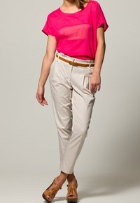 Różowa przezroczysta bluzka z krótkim rękawem, kremowe spodnie o tapered z plisami oraz brązowe sandały ze szczegółami w postaci pasków. Pasek w zestawie.