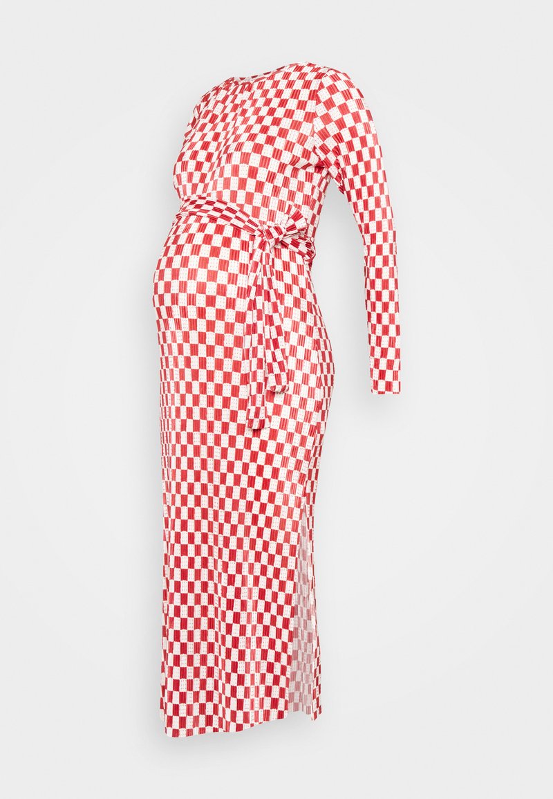 Vestido de maternidade em xadrez vermelho e branco, com mangas longas, corpete ajustado e cintura com laço. Apresenta uma fenda lateral para maior facilidade de movimento.
