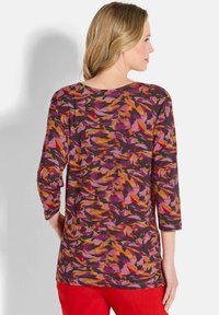 Langarmbluse mit einem mehrfarbigen, abstrakten Muster in den Farbtönen Pink, Orange und Schwarz, einem runden Halsausschnitt und einer rückseitig zentrierten Naht.