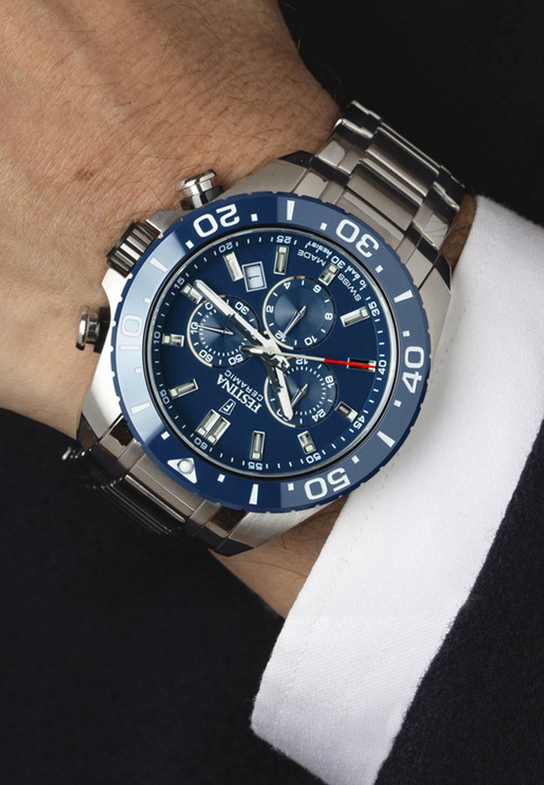 Orologio cronografo in acciaio inossidabile con quadrante blu, indicatori delle ore luminosi e dettagli argentati. Dotato di tachimetro e visualizzazione della data.