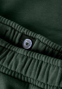 Pantalons en tricot de couleur vert foncé avec taille élastique et bouton d'ajustement à l'intérieur pour personnaliser la taille.