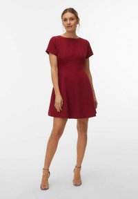 Bordo kratka haljina s pripijenim korpicom, okruglim izrezom i kratkim rukavima. Tkanina je glatka, suknja se širi i pada iznad koljena.