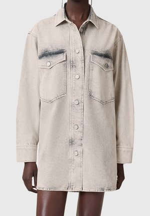 Lyse vasket denim langærmet jakke med knaplukning foran og to brystlommer med klap, båret af en person.