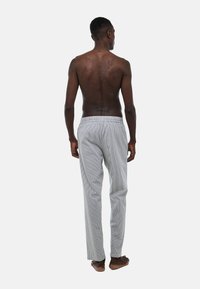 Pantalons de pyjama rayés avec une taille élastique, en tissu léger, coupe droite et rayures verticales blanches et grises.