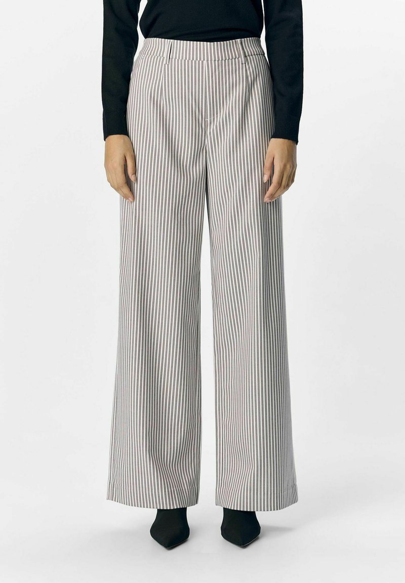Weit geschnittene Hose im gestreiften Muster mit hoher Taille, aus leichtem Stoff in einer neutralen Farbpalette, kombiniert mit schwarzen Absätzen.