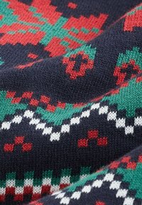 Strickstoff in Marineblau mit einem geometrischen Muster. Besitzt rote und grüne Motive, weiße Akzente und eine weiche, strukturierte Oberfläche.