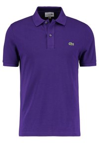 Camisa polo morada hecha de tela texturizada que presenta un cuello, una tapeta de dos botones y un logo bordado en verde en el lado izquierdo del pecho.