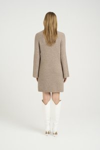 Rochie tricotată de coloră bej deschis, până la mijlocul coapsei, cu mâneci largi, textură cordonată, asortată cu cizme albe cu toc stiletto până la genunchi.