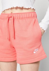 Růžové šortky ze směsi bavlny s elastickým pasem a šňůrkou, s bílým vyšívaným logem Nike na levé straně.