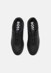 Black synthetic sneakers with round toe, textured details, lace-up design, and "BOSS" branding on the insoles.