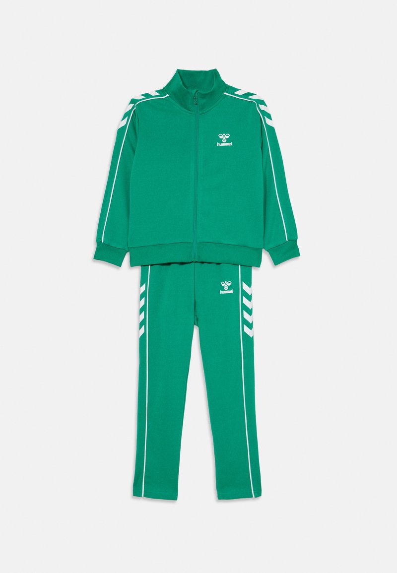 Zielony dres wykonany z miękkiego materiału, składający się z kurtki na zamek błyskawiczny i dopasowanych spodni. Udekorowany białymi paskami oraz logo na klatce piersiowej i udzie.