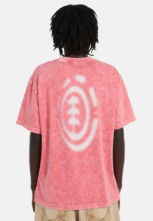 Różowy bawełniany t-shirt z krótkim rękawem, z fakturowanym tyłem ozdobionym białym, kropkowanym wzorem graficznym. Luźny krój i okrągły dekolt.