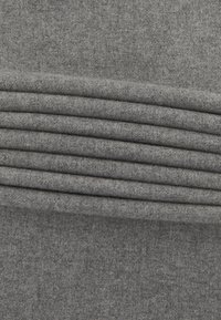 Grå fleece-stof med en blød tekstur, der har vandrette folder langs den øverste kant, hvilket skaber et lagdelt udseende.