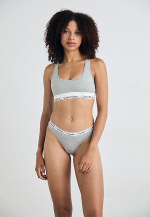 Grijze katoenen sportbeha en slipset met een brede elastische band met het "Calvin Klein" logo. Gladde textuur en een scoop halslijn ontwerp.