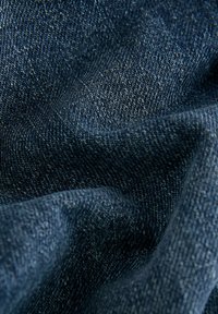 Tela de mezclilla azul oscuro con una superficie texturizada, que presenta un patrón de tejido suave y ligeramente visible, con una cualidad de caída suave.