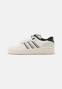 White leather sneaker with black accents, three grey stripes, round toe, and textured rubber sole. Features lace-up closure and cushioned collar.