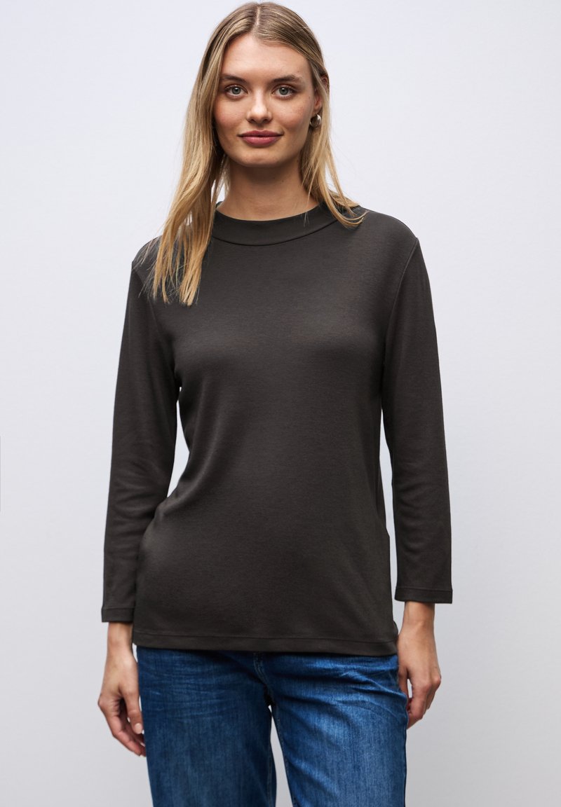 Bruine langemouwen t-shirt met een ronde hals, een gladde textuur en een slim fit silhouette, gecombineerd met blauwe spijkerbroek.