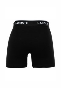 Czarne bawełniane szorty bokserskie z białą, markową elastyczną talią. Gładka tekstura i dopasowany krój z nogawkami o średniej długości.