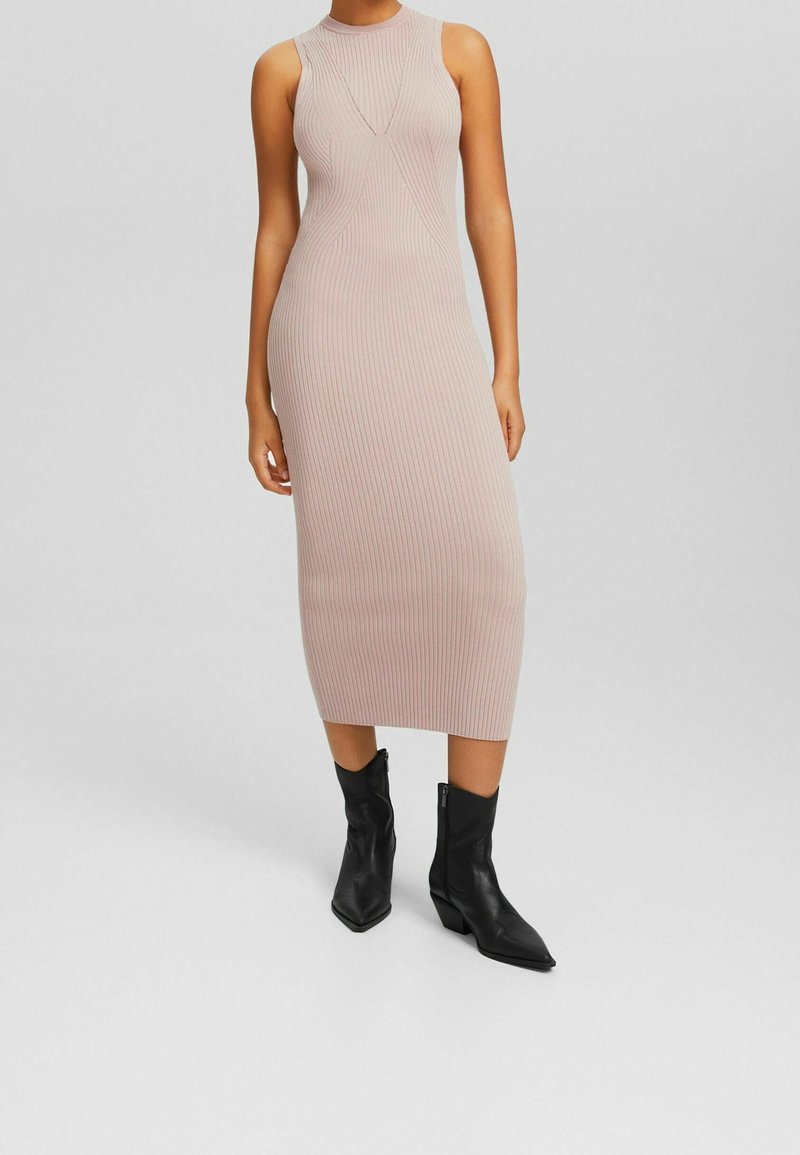 Robe midi en tricot rose clair avec texture côtelée, design sans manches et col rond, accompagnée de bottines noires à bout pointu.