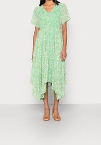 Grön blommig midiklänning med V-ringning, korta ärmar och asymmetrisk nederkant; lätt, flödande tyg med en texturerad yta.