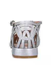 Sandalo argento con design aperto, caratterizzato da un motivo di perline, fibbia regolabile e suola piatta con fondo marrone.