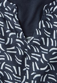 Tessuto blu navy con un motivo astratto bianco, dotato di scollatura a V e maniche corte. Il materiale appare morbido con una superficie leggermente texture.