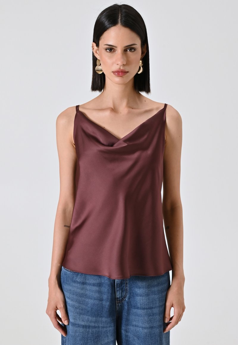 Ärmelloses Top mit Stehkragen aus dunkelburgunderfarbenem Satin, das eine glatte Textur und eine lässige Passform bietet. Kombiniert mit blauen Jeans.