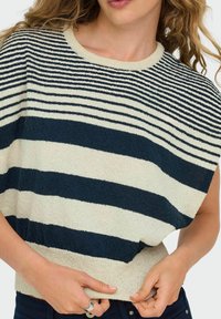 Maglione a righe in crema e blu navy. Collo rotondo, vestibilità morbida, tessuto testurizzato, con righe di larghezza variabile. Orlo inferiore a coste.