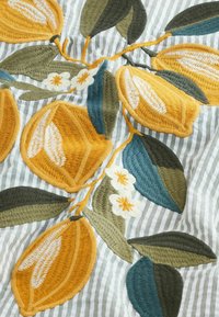  Haft przedstawiający żółte cytryny z białymi kwiatami i zielonymi liśćmi na szarym tle w białe paski.