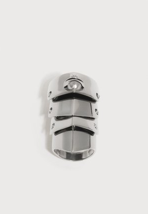 Adjustable silver metal ring with three articulated overlapping plates, creating a segmented, armor-like design.