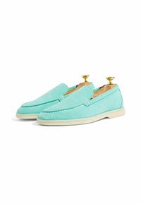 Mocasines de ante turquesa con detalles de costura y una suela de goma crema. Equipados con árboles de zapatos de madera con pomos dorados.