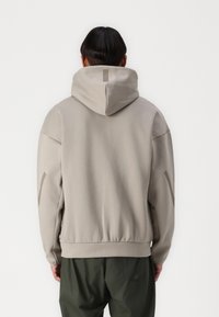 Hoodie vaalea harmaa, rento malli, ribbireunat ja yksityiskohtia hihoissa; valmistettu sileästä kankaasta, jossa on pehmeä tekstuuri.