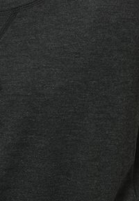 Tejido de sudadera gris oscuro que muestra una textura suave y un acabado liso, con costuras visibles a lo largo del escote. No hay patrones ni acentos presentes.